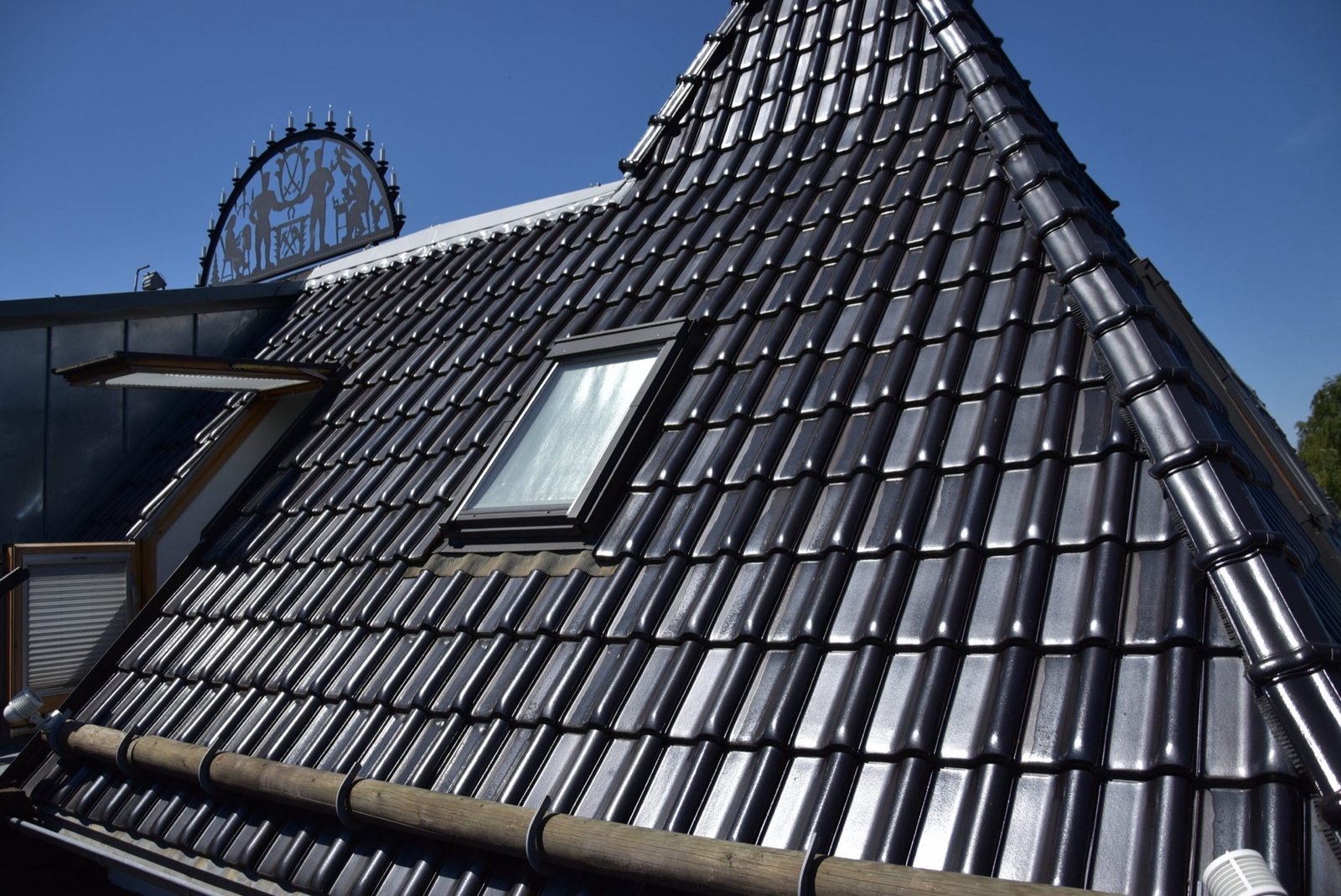 Frisch eingedecktes Steildach mit anthrazitfarbenen Dachziegeln vor blauem Himmel